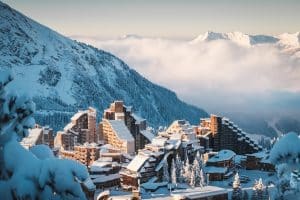 Avoriaz ski resort under fresh snow, with wooden alpine buildings overlooking a cloud-filled valley in the French Alps